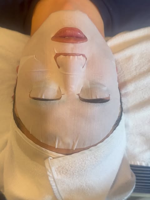 A client relaxing in a sheet mask on the treatment bed